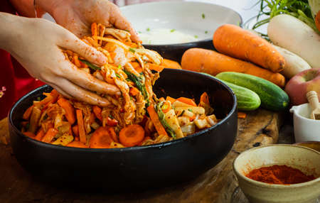 Hand holding knife and slice kimchi cabbage on wooden cutting board for cooking, Korean foodの写真素材
