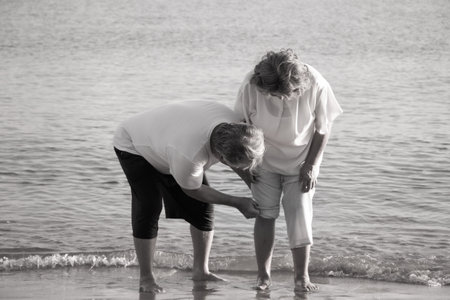Elderly couples take care of each other while older women suffer from knee pain.の写真素材