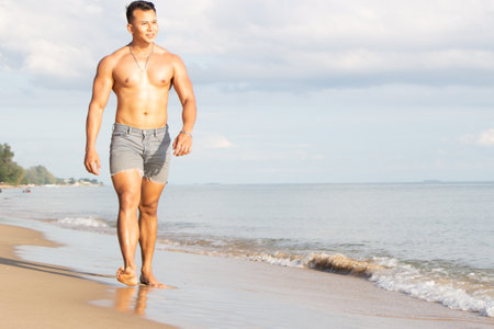 Muscular model young man walking on sea shore. asia man feeling relax on beach summer vacationの写真素材