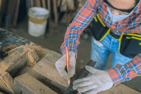 carpenter is working in a woodworking office.caucasion white Carpenter using tape measure to measure distance and marking with pencilの写真素材