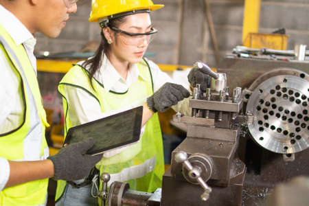 engineering working in factory concept.Two engineer worker working together with safety uniform. Factory worker and female manager discussing about work in metal industry factory.の写真素材