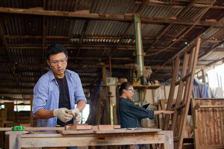 Two asian carpenters in a construction workshop. business man and woman working together woodworkの写真素材