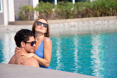 Sexy happy caucasion white couple embracing in swimming pool vacationの写真素材