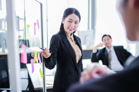asia business man and woman pointing to paper   on glass board explain document with manager in the office.businesswoman in meeting with colleagues, gesturing.Selective Focusの写真素材