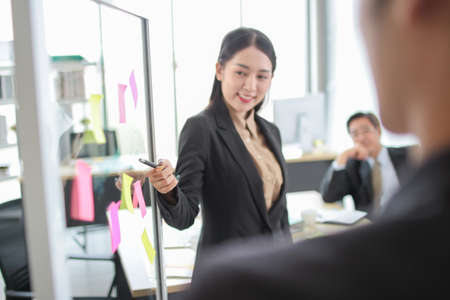 asia business man and woman pointing to paper   on glass board explain document with manager in the office.businesswoman in meeting with colleagues, gesturing.Selective Focusの写真素材