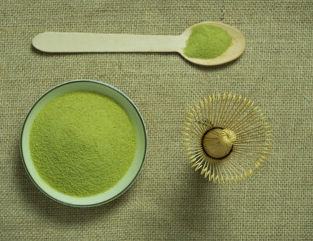 close up green tea, matcha power and whisk a cup of hot green tea on wooden table.traditional...