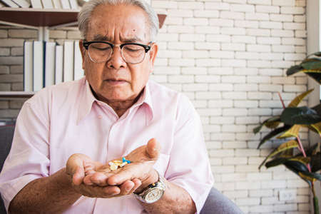 senior man at the nursing home concept.Elderly man looked unhappy at the pill in his hand.の写真素材