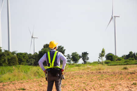 rear view man engineer wearing Personal protective equipment working in wind turbine farm background copy spaceの写真素材