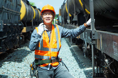 Inspector Engineering wearing helmet and vest worker unifrom checking railway construction work on rail track. Asian workers are using a walkie talkie to coordinate.の写真素材