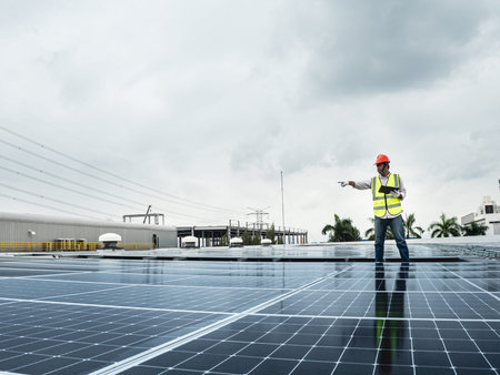 male engineer checks a photovoltaic (solar) plant and uses a recording tablet. mechanic in...