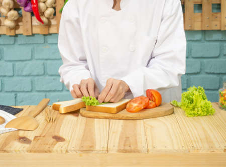 Asian woman in chef's uniform is cooking in the kitchenの写真素材