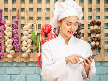 Asian woman in chef's uniform is cooking in the kitchenの写真素材