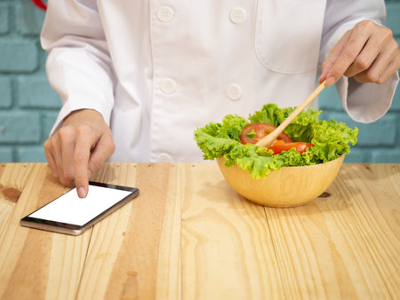 Asian woman in chef's uniform is cooking in the kitchenの写真素材