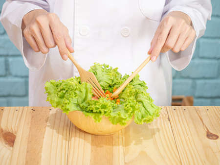 Asian woman in chef's uniform is cooking in the kitchenの写真素材