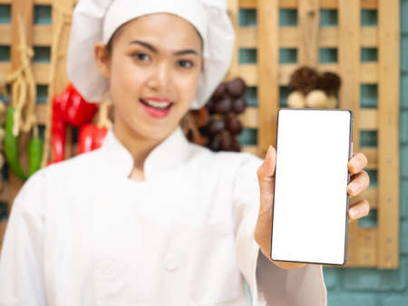 Asian woman in chef's uniform is cooking in the kitchenの写真素材