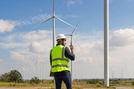 engineer team working in wind turbine farm. Renewable energy with wind generator by alternative energy concept. engineering stood with his arms crossed and looked at the camera.の写真素材