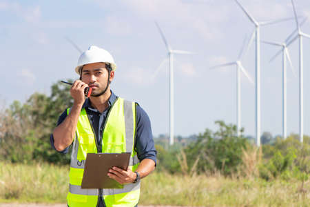 engineer team working in wind turbine farm. Renewable energy with wind generator by alternative energy concept. engineering stood with his arms crossed and looked at the camera.の写真素材