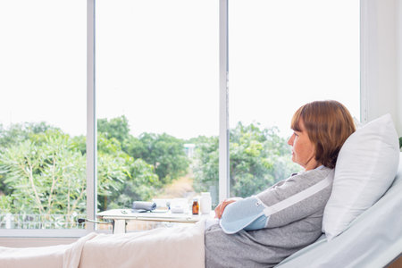 Senior woman sitting on sofa in living room at home and looking at window