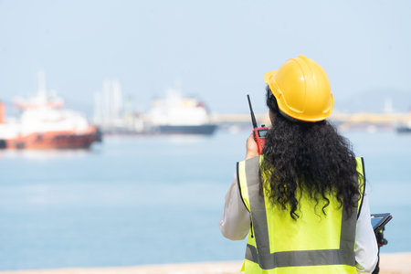 Asian Female Engineer Holding Walkie-Talkie with Marine Ship Background.の写真素材