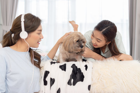 Asian female friend having fun with dog in bedroom.の写真素材