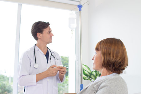 Doctor and patient discussing something while sitting at the table in the hospitalの写真素材