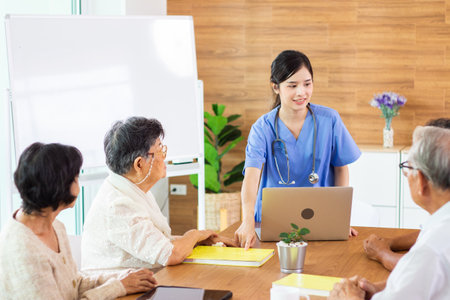 Asian nurse and senior patient discussing something while sitting at the table.の写真素材