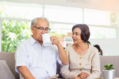 Asian senior couple drinking coffee and talking to each other at home.の写真素材