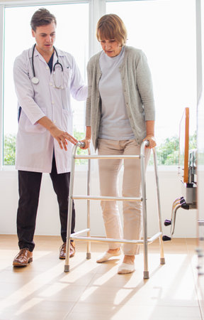 Doctor helping senior patient with walker in hospital. Healthcare and medical service.の写真素材