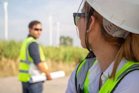 Female engineer looking at wind turbine with male worker in the background.の写真素材