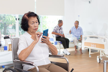 Elderly woman using mobile phone in nursing home with her familyの写真素材