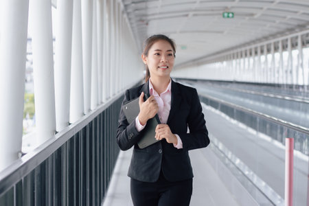 young Asian businesswoman in black suit using digital tablet and standing on walkway station with copy space.の写真素材