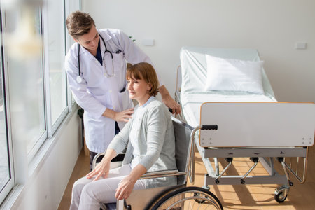 Doctor and patient discussing something while sitting in the wheelchair at the hospitalの写真素材