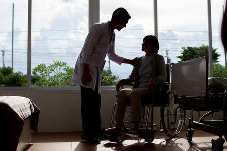 Doctor taking care of a patient in a wheelchair at the hospital.の写真素材
