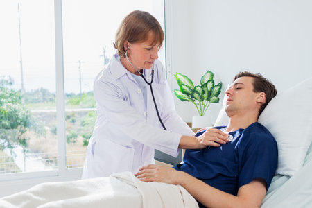 Doctor examining a patient in ward at hospital. Focus on the manの写真素材