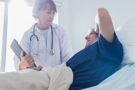 Doctor and patient discussing something while lying on bed at hospital. Doctor and patientの写真素材