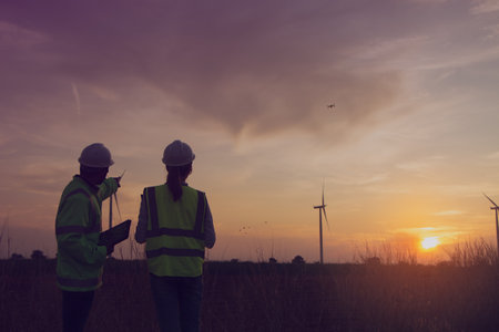 silhouette engineer and wind turbine on the field with sunset backgroundの写真素材