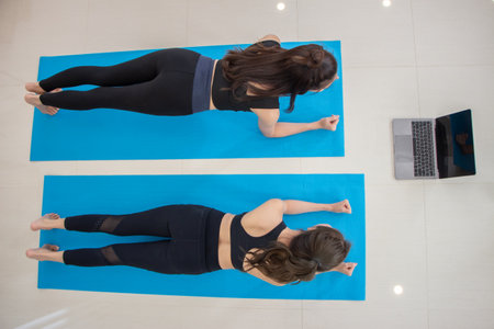 Asian female friends exercising at home. fitness girl in athletic exercise clothes doing a plank workout.の写真素材