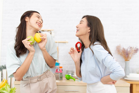 happy young asian women having fun with apple in the kitchen at homeの写真素材