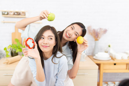 happy young asian woman with apple and lemon in living room at homeの写真素材