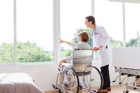Doctor pushing a wheelchair with a patient in a hospital. Healthcare and medical concept.の写真素材