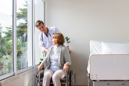Doctor taking care of senior woman in wheelchair at nursing home or hospitalの写真素材