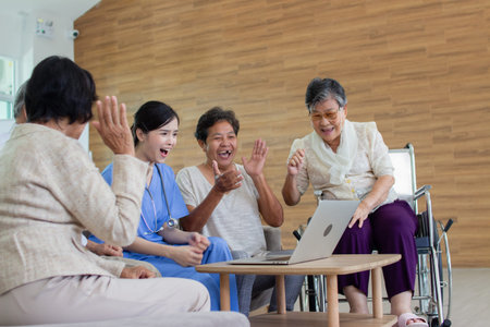 asian senior people sitting on wheelchair and using laptop at nursing homeの写真素材