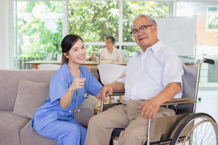 Asian senior patient sitting in wheelchair with nurse or caregiver at nursing homeの写真素材