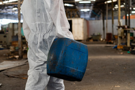 Worker in a chemical protective suit holding a blue canister.の写真素材