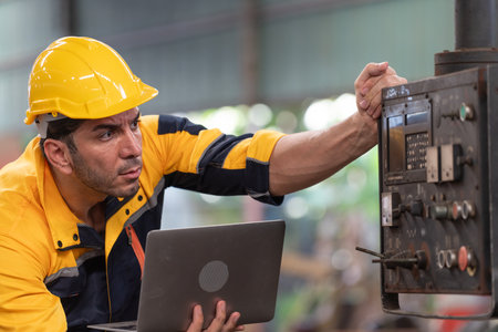 engineer or factory worker using laptop computer for working with machine in factoryの写真素材