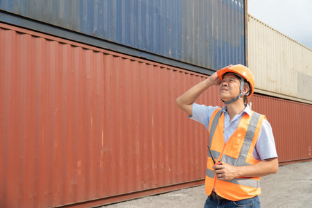 Portrait of Asian male worker wearing safety helmet and reflective vest at container yard