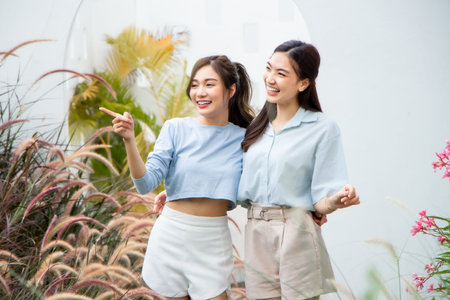 two asian women standing in the garden and smile happily at the cameraの写真素材