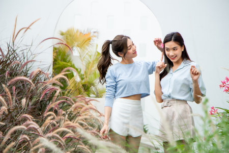 Two young asian women standing in the garden and looking at each otherの写真素材