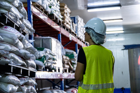Female industrial engineer wearing a white helmet while standing in a heavy industrial factory.