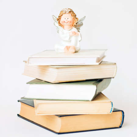 Darling, smiling angel sits on pile of books.の写真素材